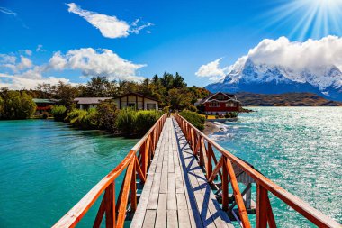 Pehoe Gölü 'ndeki köprüden adaya. Los kuernos 'un karla kaplı siyah uçurumları. Torres del Paine Parkı. Eriyen buzulların suyunun gök mavisi var. Chiles Patagonya.