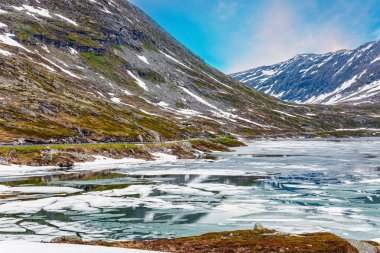 Norveç 'te büyülü yerler. Temmuz ayında Djupvatnet Gölü 'nün çok soğuk ve berrak suyu buzla kaplıdır. Dağlar yeni yağmış karla kaplıdır. Kar Kraliçesi Krallığı. 