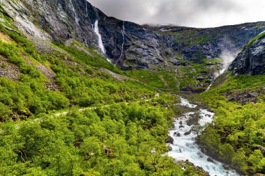 Stigfossen şelalesi. Trollstigen Norge - Norveç 'in en popüler turistik mekanı. Kanyonun yeşil yamaçları. Drone film çekiyor. 