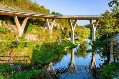 Eski Avrupa 'yı büyülüyor. Sıcak yaz günbatımı. Hırvatistan 'a git. Slunj kasabası, Rastoke. Modern viyadük, Slunjcica Nehri 'nin pürüzsüz ve berrak suyuna yansıyor.