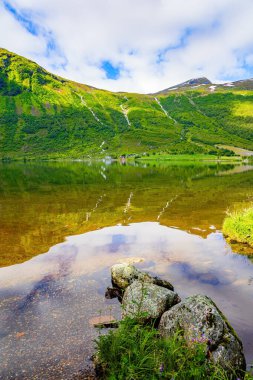 Temiz şeffaf suyu olan derin bir göl. Su yemyeşil bulutları, mavi gökyüzünü ve ormanlı kıyıları yansıtır. Eidsvatnet - Norveç 'teki görkemli göl. Yeşil Dünya. İskandinavya 'da yaz. 
