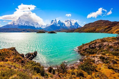 Los Kuernos 'un muhteşem kar kaplı siyah uçurumları. Parlak soğuk güneş. Lago Pehoe. Torres del Paine Parkı. Chiles Patagonia. Eriyen buzulların suyunun gök mavisi var..