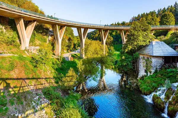 Modern viyadük, Slunjcica Nehri 'nin pürüzsüz ve berrak suyuna yansıyor. Eski Avrupa 'yı büyülüyor. Sıcak yaz günbatımı. Hırvatistan 'a git. Slunj kasabası - Rastoke.