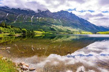Temiz şeffaf suyu olan derin bir göl. Suyun pürüzsüz yüzeyi korunan ormanları yansıtır. Norveç. Eidsvatnet Norveç 'in en güzel gölleri. 