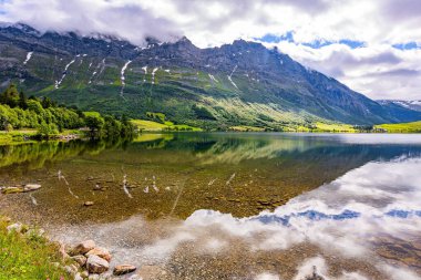 Deep lake with clean transparent water. The smooth surface of the water reflects protected forests. Norway. Eidsvatnet most beautiful Norwegian lakes.  clipart