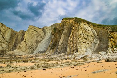 Portio Plajı, Cantabria Plajları. Dev, pürüzsüz gri kayalar ve pürüzsüz kumsal. İspanya 'nın Playa di Arnia plajında öğle vakti. Atlantik kıyısında rüzgarlı bir gün. 