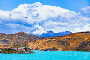 Los Cuernos 'un muhteşem kar kaplı siyah uçurumları. Parlak soğuk güneş. Lago Pehoe. Torres del Paine Parkı. Eriyen buzulların suyunun gök mavisi var. Chiles Patagonya. 