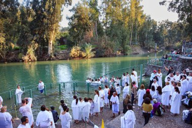 YARDENIT, ISRAEL - 21 HAZİRAN 2012: Beyaz vaftiz gömleklerine inanan bir grup Ürdün Nehri 'nin sularına girer. Yardenit Ürdün Nehri 'nin Kinneret Gölü' nden çıkış noktası.