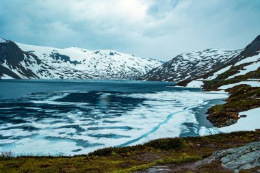 Temmuz ayında Djupvatnet gölünün çok soğuk suyu buzla kaplıdır. Dağlar yeni yağmış karla kaplıdır. Kar Kraliçesi Krallığı. Norveç 'te sihirli yerler. 