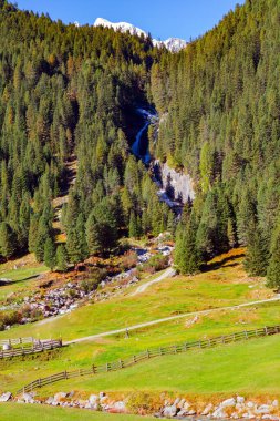 Resimli şelale. Erimiş gök mavisi akıntısı Krimmml Falls vadisine akar. Avusturya Alplerinin güzel doğal alanları. Sonsuza dek yeşil ormanlarla kaplı dağlar.. 