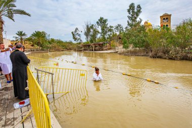 QASR EL YAHUD, ISRAEL - 2 Mart 2020: genç kadın suya girer. İsa Mesih 'in vaftiz edildiği yer. Ürdün Nehri 'nde tarihi bir yerde vaftiz töreni.. 