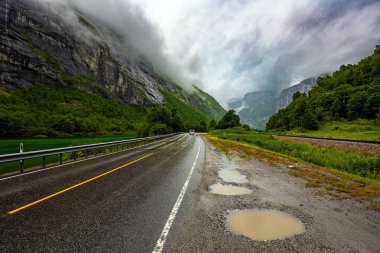 Otoyol. Buz şelalesi yamaçlardan aşağı akıyor. Norveç 'in batı kıyısındaki Romsdalen' deki Troll Wall. Norveç 'te karanlık ve soğuk bir yaz. Dağları saran dramatik bulutlar