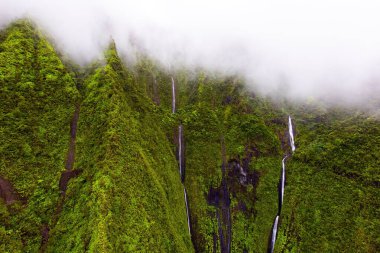 Polinezya Adaları. Kapıları kapalı helikopter uçuşu. Kuş gözüyle Kauai adasının göz kamaştırıcı manzarası. Adanın kıyı şeridine yürüyüş için ulaşılamaz. Dağlarda sis ve şelaleler.