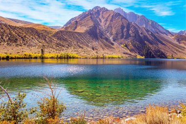 Mahkûm Gölü. ABD. Kaliforniya mı? Kayalık kıç sakin suda parlar. Granit kayalar suya yansıyor. Göl buzul erimiş suyla beslenir.. 