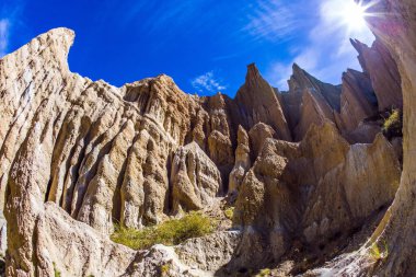 Çamur, alüvyon ve çakıldan oluşan görkemli kayalar. Mavi açık gökyüzü ve parlak güneş. Yeni Zelanda 'nın zirveleri. Yeni Zelanda, Omarama Clay Cliffs. Fotoğraf Fishai lens ile çekildi.. 