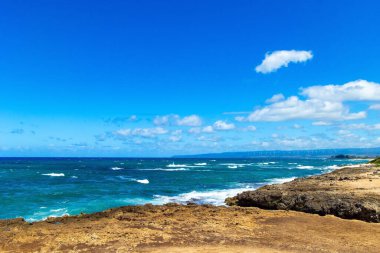 Pasifik Okyanusu kıyısında güçlü bir okyanus sörfü. Sahile dağılmış devasa keskin kayalar. Muhteşem Oahu adası.. 