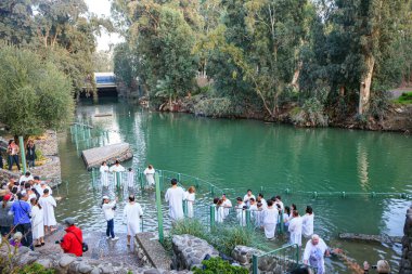 YARDENIT, ISRAEL - 21 HAZİRAN 2012: Beyaz vaftiz gömleklerine inanan bir grup Ürdün Nehri 'nin sularına girer. Ortodoks ve Katoliklerin vaftiz ayini. 