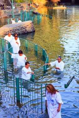 YARDENIT, ISRAEL - 21 HAZİRAN 2012: Beyaz vaftiz gömleklerine inanan bir grup Ürdün Nehri 'nin sularına girer. Yardenit, Ürdün Nehri 'nin Celile Denizi' nden çıkış noktasıdır.. 