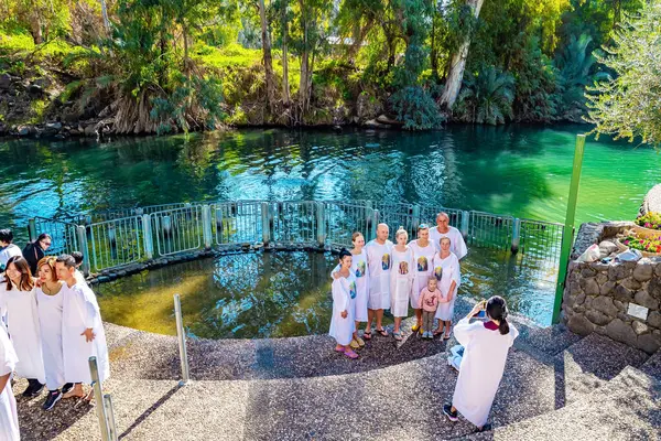 YARDENIT, ISRAEL - 21 HAZİRAN 2023: Yardenit Hıristiyanlar için vaftiz merkezi. Güneşli kış günü. Vaftiz gömleği giyen neşeli hacılar Ürdün Nehri 'nin soğuk suyunda vaftiz edilirler.