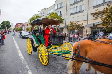 SAN FRANCISCO, ABD - 11 Ekim 2009: Kırmızı karnaval kostümlü yaşlı kadın iki atın çizdiği eski bir arabaya biniyor. Columbus Günü 'nün onuruna binicilik geçidi 