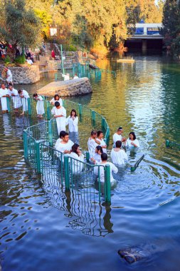 YARDENIT, ISRAEL - 21 HAZİRAN 2012 İnananların Vaftiz Ayini. Beyaz vaftizli bir grup inanan Ürdün Nehri 'nin sularına girer. Soğuk güneşli Ocak günü.