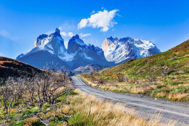 Los Cuernos 'un karla kaplı siyah uçurumları. Şili Patagonya 'ya destansı bir gezi. Amerika 'nın güney ucundaki olağanüstü manzaralar. And Dağları. Tepeler arasındaki toprak yol