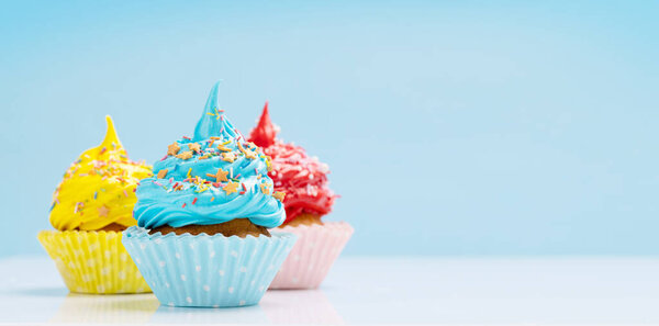 Colorful cupcakes on blue background with copy space