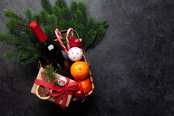 Christmas gift basket with champagne bottle, decor, gift boxes and fruits. Top view flat lay with copy space