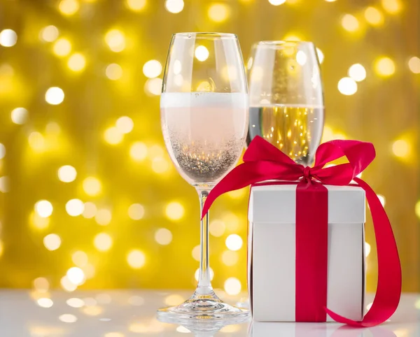 圣诞灯前的香槟酒杯和礼品盒 — 图库照片