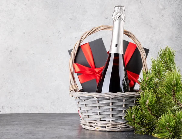 クリスマスのギフトボックスとシャンパンとあなたのクリスマスの挨拶のためのスペースを備えたバスケット — ストック写真