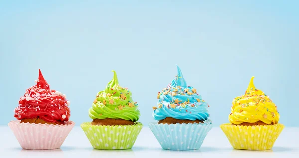 Colorful cupcakes on blue background with copy space