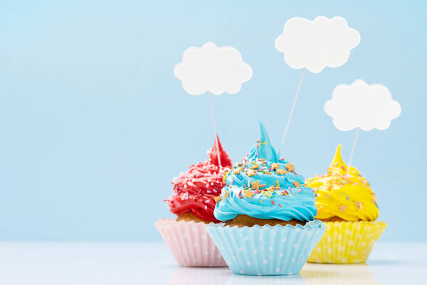 Colorful cupcakes on blue background with copy space