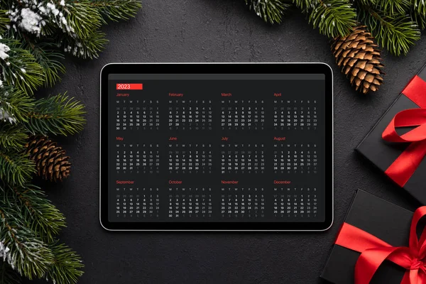 Tablet with next year calendar, gift boxes and Christmas decor. Xmas device screen template