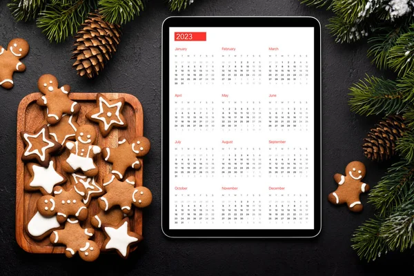 Tablet with next year calendar, gingerbread cookies and Christmas decor. Xmas device screen template