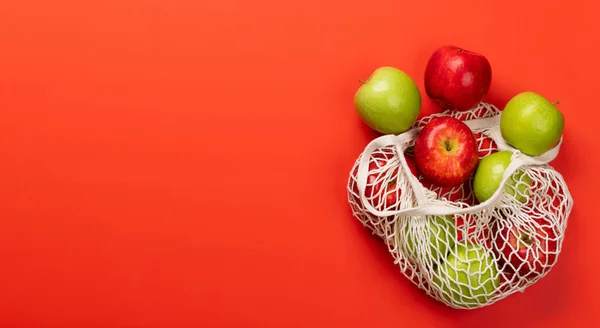 Rote Und Grüne Äpfel Netztasche Auf Rotem Hintergrund Wohnung Lag — Stockfoto