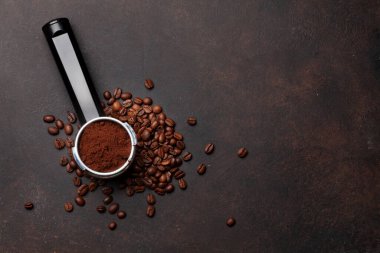 Kavrulmuş kahve çekirdeği ve filtre tutacağında öğütülmüş kahve. Üst görünüm düzlüğü kopyalama alanı ile yatıyordu