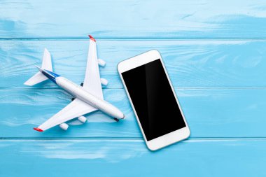 Seyahat ve tatil konsepti. Aksesuarlar ve eşyalar. Uçak oyuncağı ve akıllı telefon. Üst görünüm düzlüğü kopyalama alanı ile yatıyordu