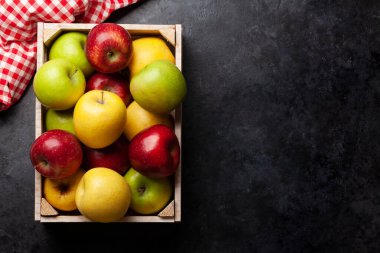 Taş masadaki kutuda renkli olgun elma meyveleri. Üst görünüm düzlüğü kopyalama alanı ile yatıyordu