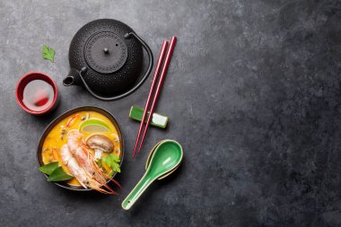 Tom Yum geleneksel Tayland çorbası deniz ürünleri, mantar, hindistan cevizi sütü ve sıcak baharatlı. Yeşil çaydanlık ve kase ile. Kopyalama alanı olan üst görünüm