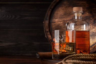 Bardak ve şişe konyak, viski ya da altın rom. Kopya alanı olan eski ahşap fıçının önünde.