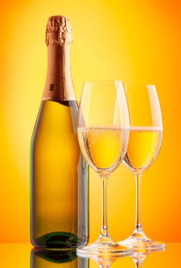 İki şampanya bardağı ve köpüklü şarap şişesi. Sarı arkaplan