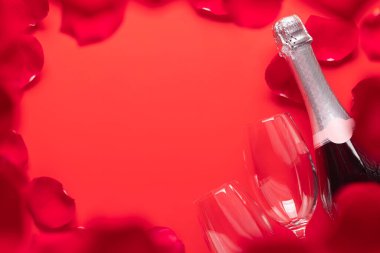 Şampanya ve gül yapraklı sevgililer günü kartı. Kırmızı arkaplanda selamlarınız için yer var. Düz yatıyordu