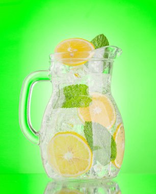 Limonlu, naneli ve buzlu limonata sürahisi. Yeşil arkaplan