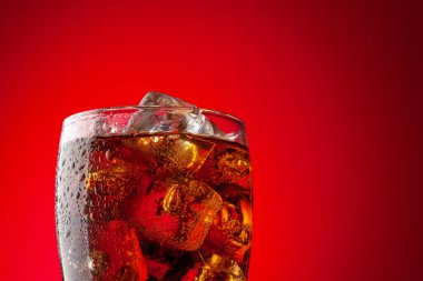Buzlu kola. Buz küplü taze, soğuk bir içecek. Kopyalama alanı olan kırmızı arkaplan
