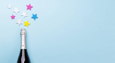 Şampanya şişesi ve mavi arka planda yıldız dekoru. Kopyalama alanı olan düz