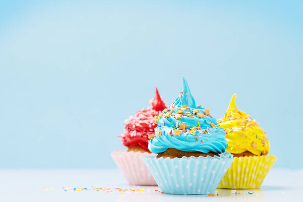 Colorful cupcakes on blue background with copy space
