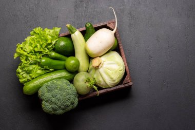 Sağlıklı yeşil sebze ve meyvelerle dolu ahşap bir kutu. Kopyalama alanı olan düz