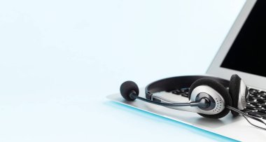 Mavi arka planda dizüstü bilgisayarda fotokopi alanı olan kulaklık. Hizmet veya destek şablonu