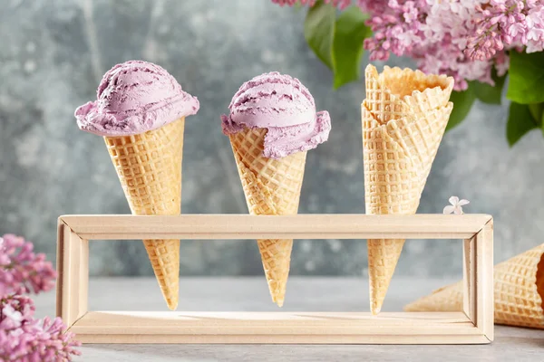 Various ice cream sundae in waffle cones and lilac flowers