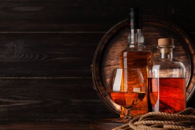 Bardak ve şişe konyak, viski ya da altın rom. Kopya alanı olan eski ahşap fıçının önünde.